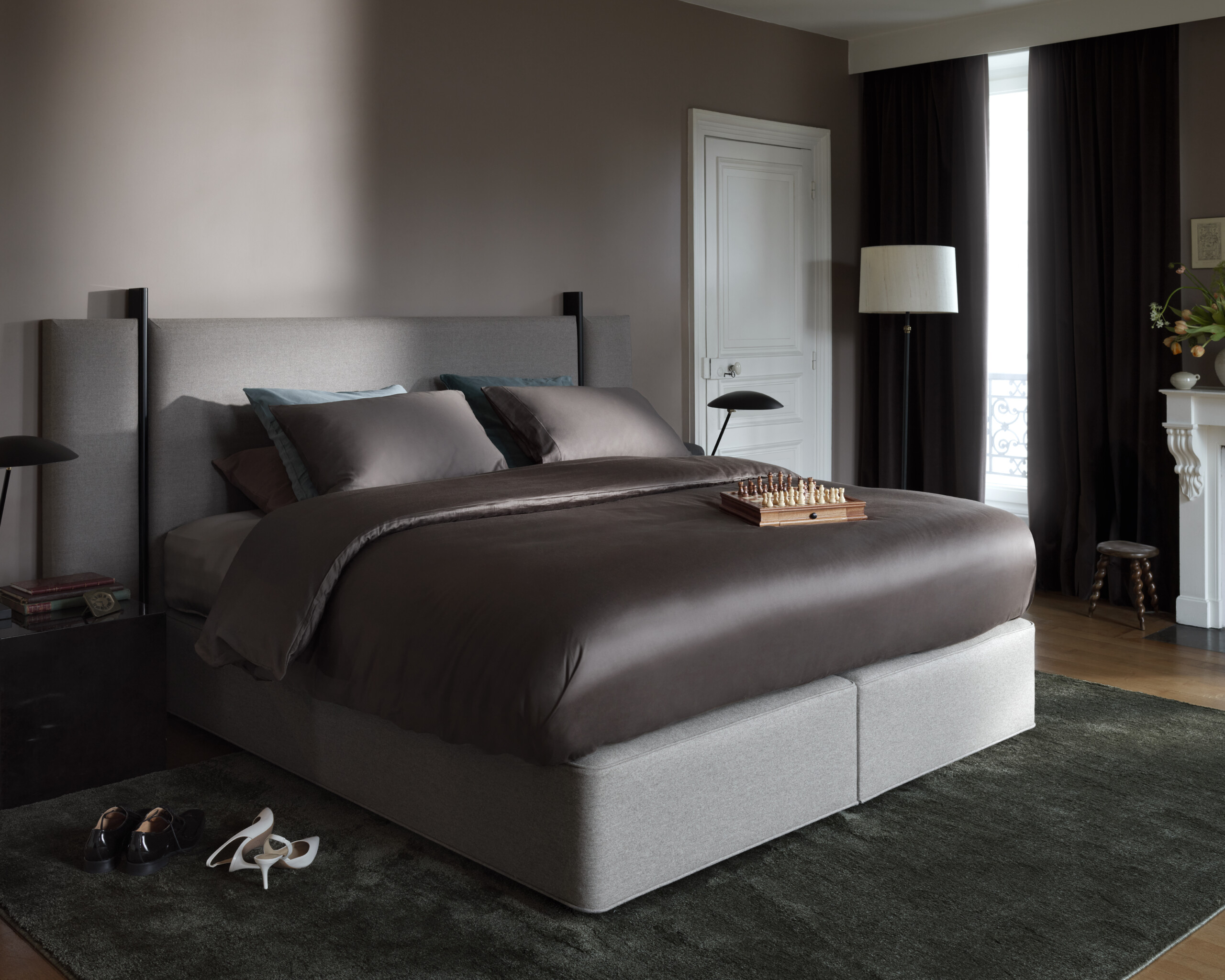 Vispring Bett mit grauem Kopfteil und dunkler Bettwäsche im Schlafzimmer