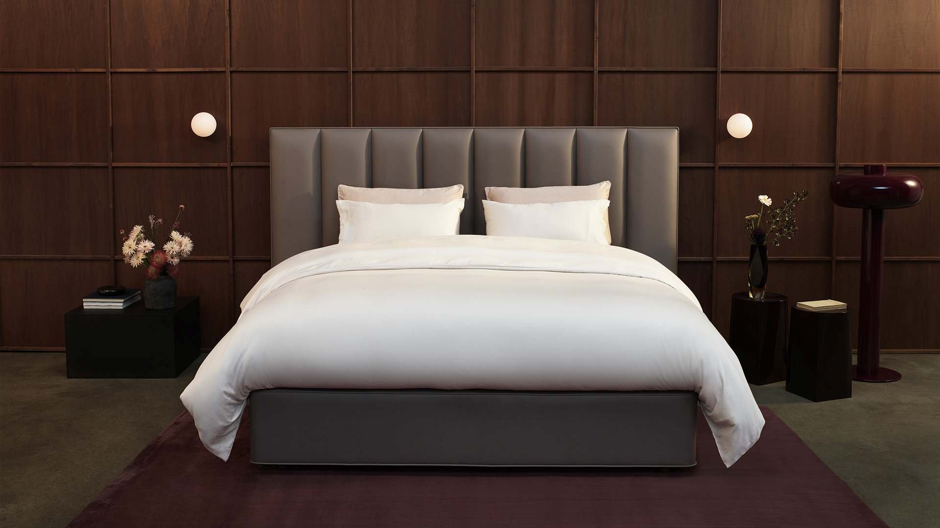 Vispring Bett der Luxe Kollektion mit taupefarbenem Kopfteil vor Holzvertäfelung