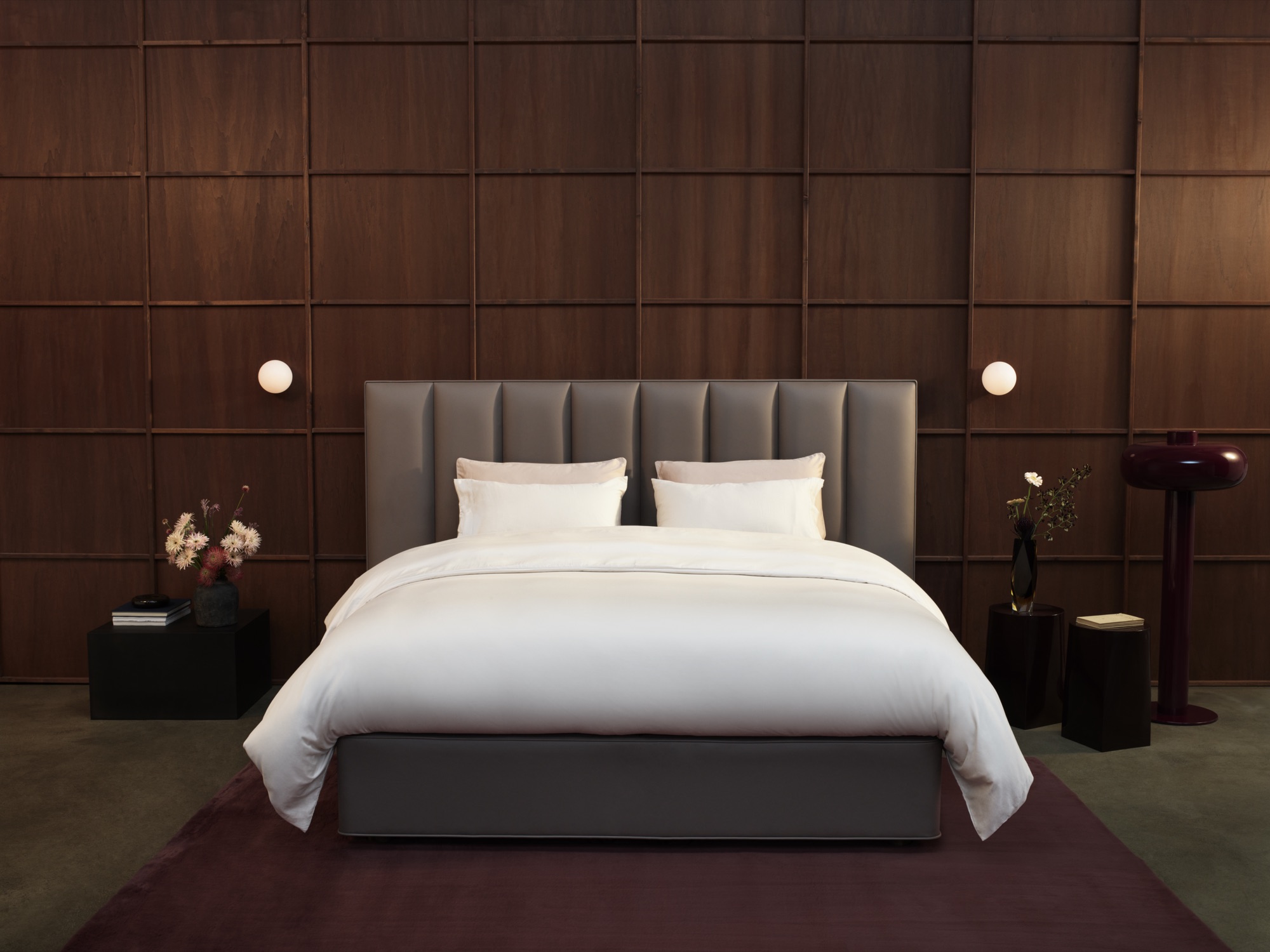 Vispring Luxe Kollektion: Bett mit taupefarbenem Kopfteil vor dunkler Holzvertäfelung
